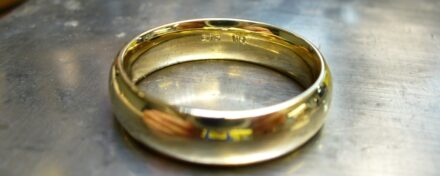 goldener ring mit gravur auf silberner werkbank